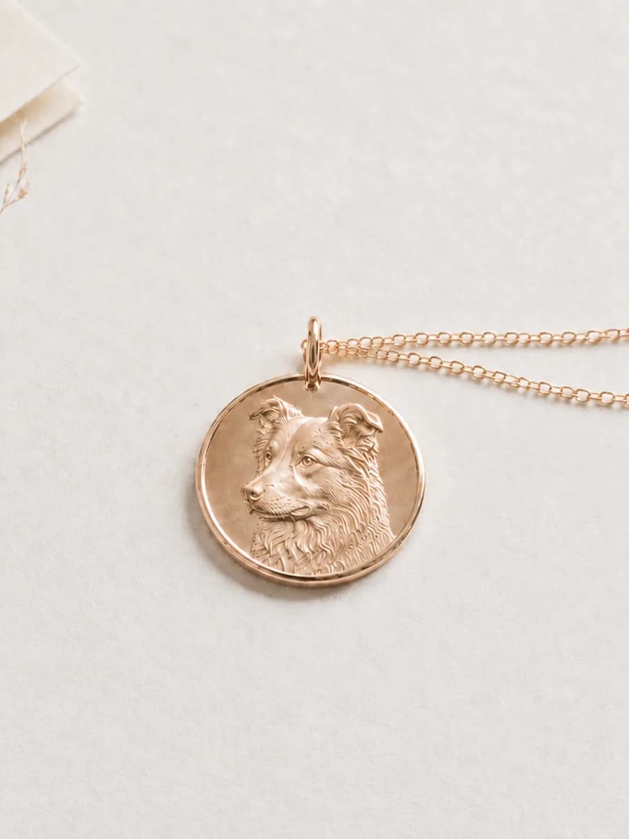 Rose gold vermeil pendant engraved with a border collie, beside a dried grass stem